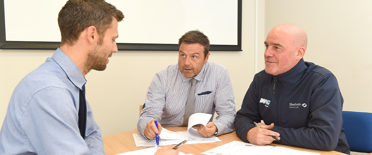 three men sat at a desk in an office at sherburn metalwork